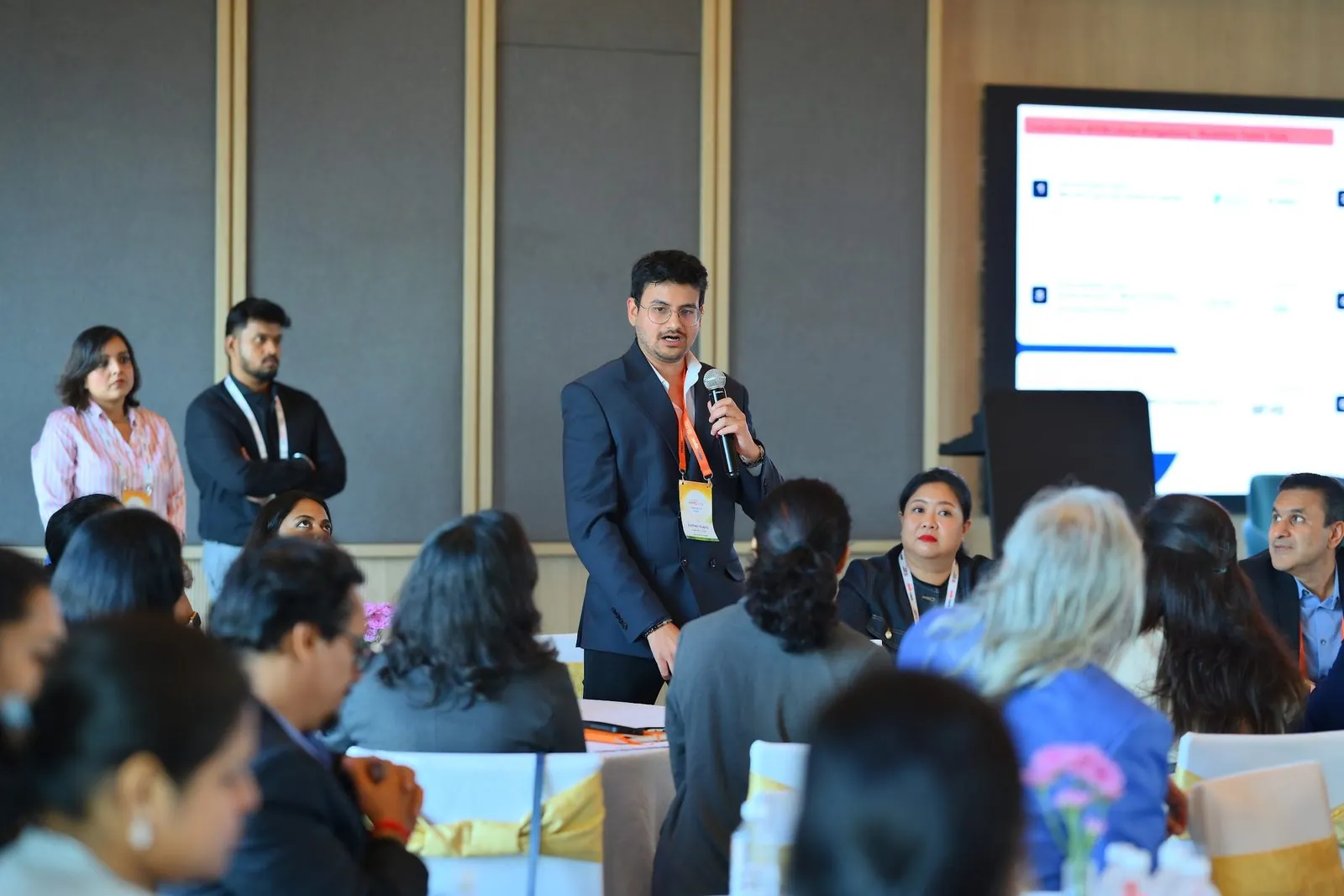 Eashan Gupta standing among the tables, talking the room through describing their own agents, at an industry conference in Bengaluru
