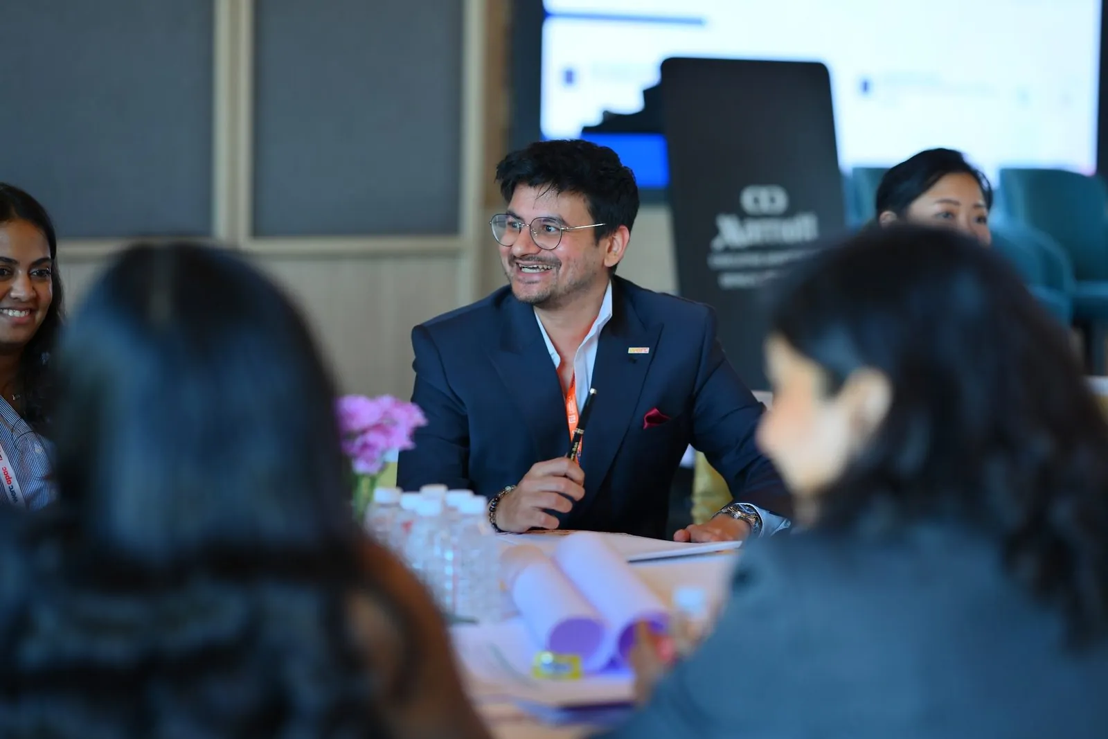 Eashan Gupta at a table with mobility leaders, smiling mid conversation, Bengaluru